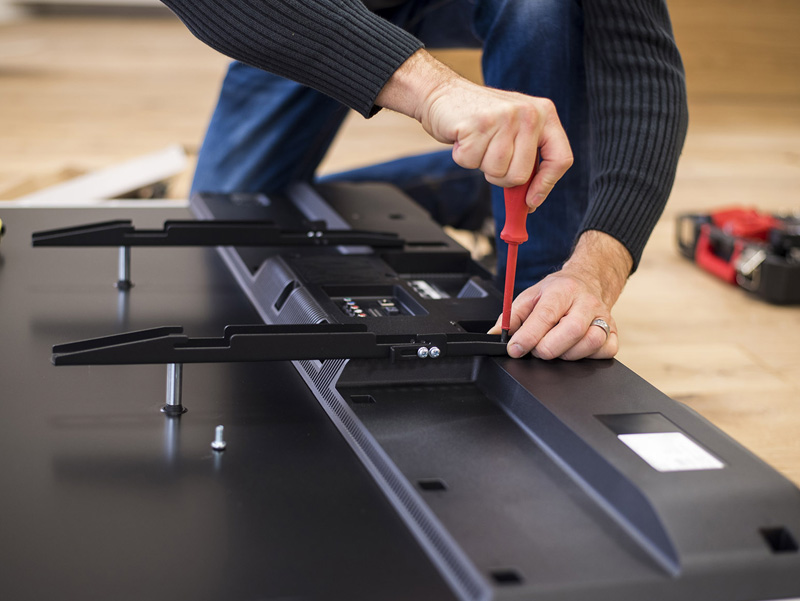 Skilled technician expertly installing a wall mount on a television.