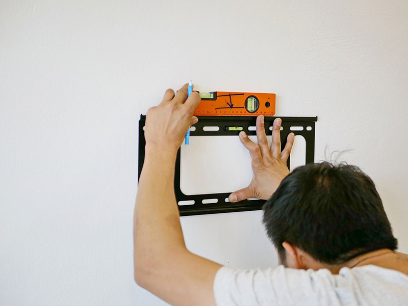 Professional technician installing a TV wall mount with precision and care.